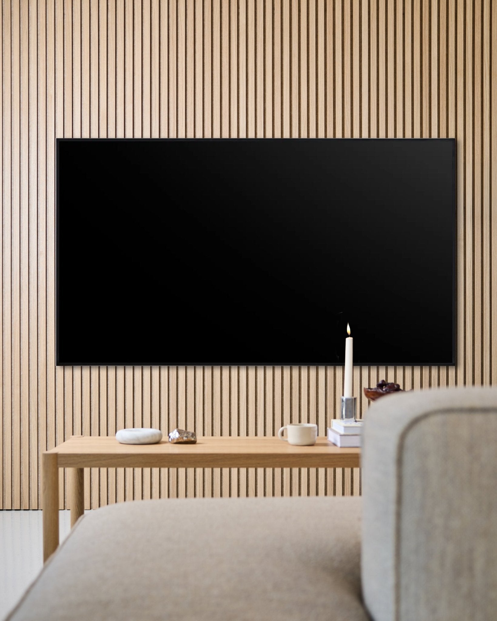 Modern living room featuring a wall-mounted flat screen TV, Akupanel wooden acoustic slat wall, and a wooden coffee table for a cozy atmosphere.